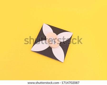 Abstract, square ceramic phone holder on yellow background