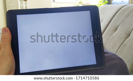 A man using tablet with empty screen while lying on the couch