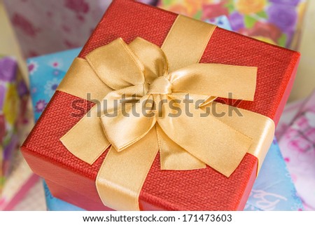 Red gift box with golden ribbon on table