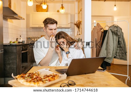 young caucasian couple spend quarantine at home together, married couple watch dangerous horror film and eat pizza, woman closed her eyes with hands