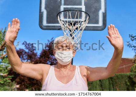 senior woman with face mask with basketball basket in background