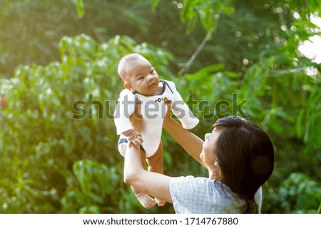 Happy asian mother playing with newborn outdoor, mum and child having fun together - Family, happiness and love and mother's day concept
