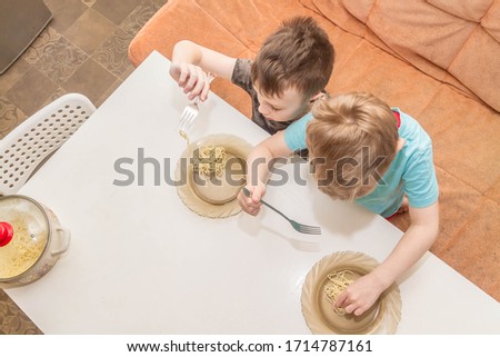 Two European boy brothers eat empty macaroni. Money crisis in the family. No food.