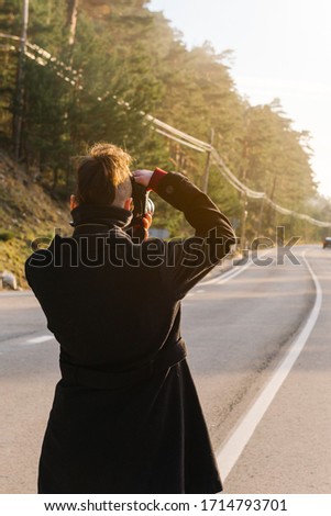Young caucasian tourist woman photographing a forest from the road. tourism, vacation and adventure concept. vertical stock photo