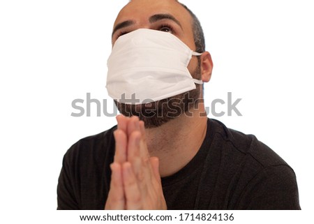 Man with a mask protects himself from the coronavirus by praying with his hands together
