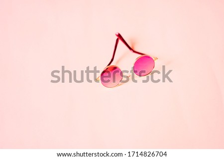 Round sunglasses with silver metal frame isolated on pink background with copy space for your text or design. Stylish accessory for summer.