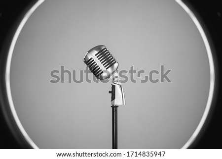 Horizontal side view of old style metallic microphone inside a professional circle light. Vintage silver microphone isolated on white background. Retro oldies music concept. Royalty-Free Stock Photo #1714835947