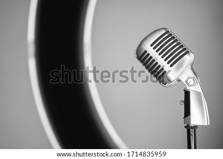 Detail of horizontal side view of old style metallic microphone inside a professional circle light. Vintage silver microphone isolated on white background. Retro oldies music concept. Royalty-Free Stock Photo #1714835959