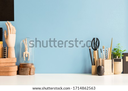 Home workspace, creative desk with wooden supplies and blue wall.