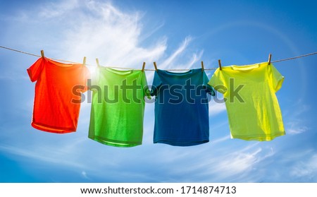 T-shirts hanging on a clothesline in front of blue sky and sun Royalty-Free Stock Photo #1714874713