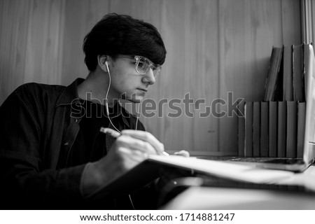 online training. home training, quarantine training. hipster guy with glasses watching a training webinar on a laptop, spending time on e-learning. distance learning. black and white photo