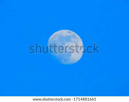 Almost full moon on afternoon blue sky