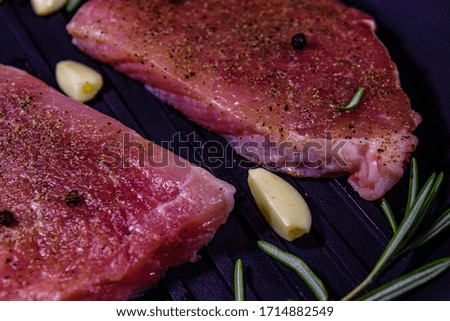 Raw steaks with garlic, rosemary and spices in cast iron grill pan