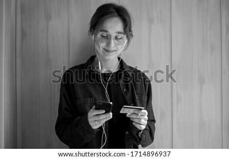 online payments. Girl holds a smartphone and a credit card. European woman shopping online. Beautiful young woman using a credit card and mobile phone for online shopping. black and white photo