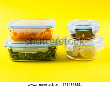 Stack of airtight glass food containers with colorful cooked vegetables on bright yellow background. Meal prep concept Royalty-Free Stock Photo #1714898551