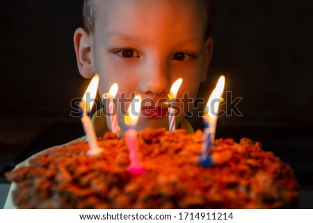 Toddler Looks at Cake with Candles. Celebrating Sixth Anniversary. Happy Birthday. Chocolate Delicious Pie. Child Makes Wish. Darkness Background
