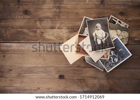 old vintage monochrome photographs, pictures taken in 1968, in sepia color are scattered on a wooden table, concept of genealogy, the memory of ancestors, family ties, memories of childhood Royalty-Free Stock Photo #1714912069