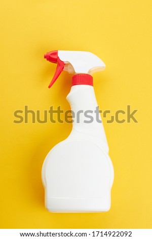 blank chemical spray bottle on a bright yellow background. copy space. cleaning and washing concept.