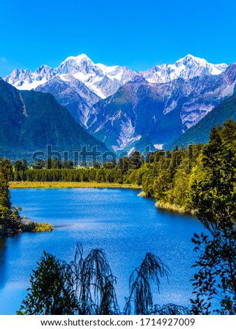 Mountain peaks covered with snow. Mirror glacial Lake Matheson surrounded by mountains Mount Cook and Mount Tasman and forests. The concept of ecological, active and photo tourism
