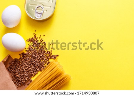 Pasta, buckwheat, eggs, canned food. Food supplies crisis food stock for quarantine isolation period on yellow background.Food delivery, Donation, coronavirus quarantine. Copyspace.