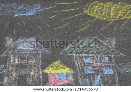 Children's multi-colored drawing on the road. The house, the sun, a cloud drawn by a child with crayons on the pavement. Colorful, beautiful image.