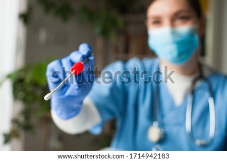 Female caucasian doctor holding a swab collection stick, nasal and oral specimen swabbing in doctor's office, patient PCR testing procedure appointment, Coronavirus COVID-19 global pandemic crisis Royalty-Free Stock Photo #1714942183