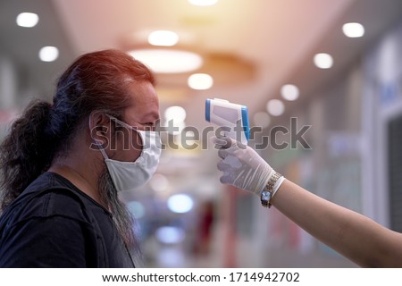  Coronavirus epidemic. Man having his temperature checked before entering the supermarket. Security procedures.                               Royalty-Free Stock Photo #1714942702