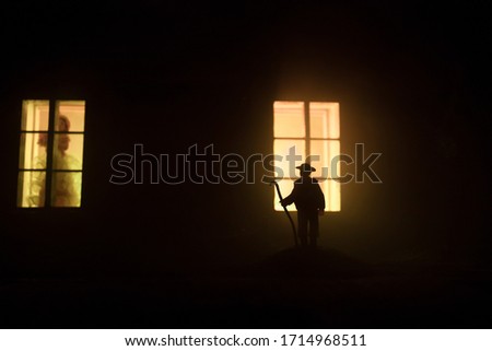 Old house with a Ghost in the forest at night. Horror silhouette at the window. Horror Halloween concept Alone man silhouette standing near window of dollhouse at night. Selective focus