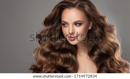 Beautiful model girl with long wavy and shiny hair . Brunette woman with curly hairstyle Royalty-Free Stock Photo #1714972834