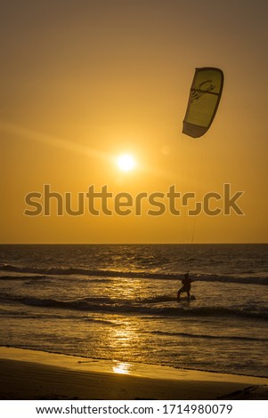 Kite-surfing on orange sunset's background in the ocean