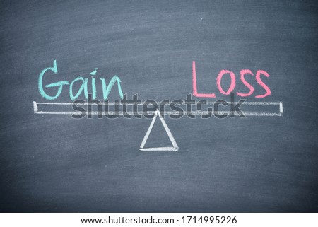 Text word gain and loss balance on seesaw drawing writing on chalkboard or blackboard background. Concept of gain and loss analysis in business, financial management and money investment. Royalty-Free Stock Photo #1714995226