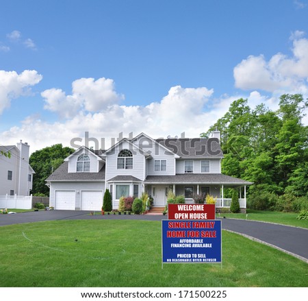Suburban McMansion Style home Circle blacktop driveway two car garage residential neighborhood blue sky clouds USA