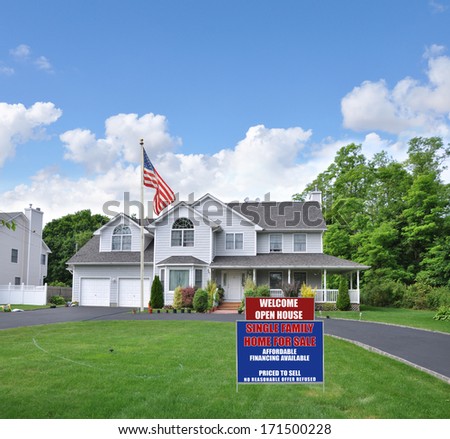 American Flag For Sale Real Estate Sign Suburban McMansion Style home Circle blacktop driveway two car garage residential neighborhood blue sky clouds USA