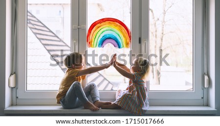 High five! Little children on background of painting rainbow on window. Photo of kids leisure at home, childcare, safety joy symbol, family life. Brother and sister on vacation.