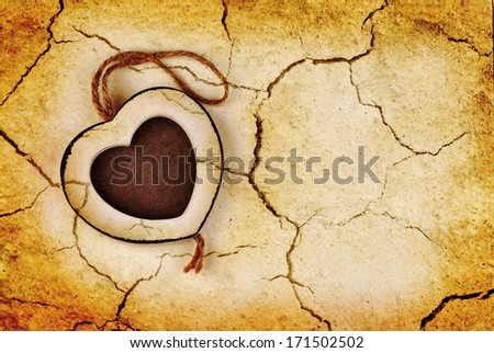 Photo frame in wood heart shape on dry cracked grunge earth background