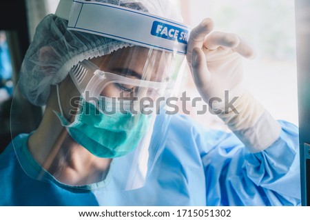 Nurse having headache and tired from work while wearing PPE suit for protect coronavirus disease. The wellbeing and emotional resilience are key components of maintaining essential care services.