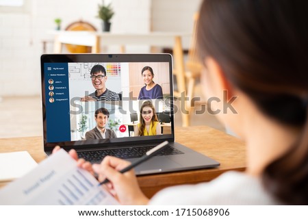 Young Asian businesswoman work at home and virtual video conference meeting with colleagues business people, online working, video call due to social distancing Royalty-Free Stock Photo #1715068906