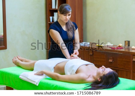 Photo of relaxed lying brunette woman receiving hands massage in the spa salon