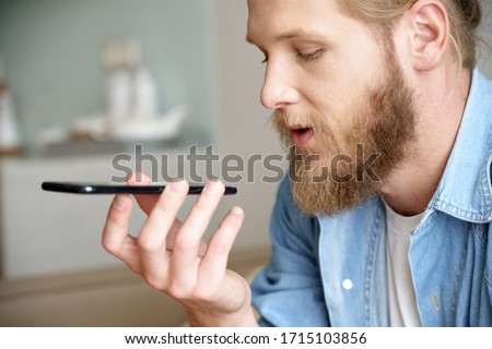 Young man hold phone speak on speakerphone using virtual digital voice recognition assistant search on smartphone at home record audio message, mobile app ai tech assistance technology concept.