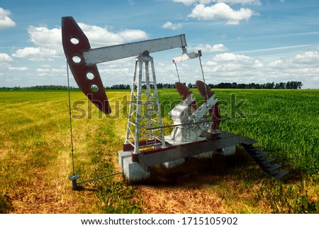 Oil pump, oil rig an industrial oil production standing in the field. Technology concept, fossil energy sources, hydrocarbons. Mixed media copy space.
