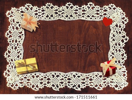 lacy frame and three small decorative gift boxes and heart shaped object on wooden table with space for your text. toned