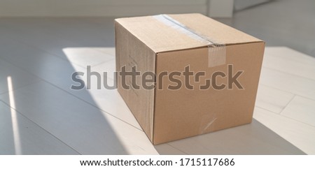 Home delivery cardboard box package delivered at doorstep on floor of entrance door. Parcel shipping for retail online shopping businesses. Royalty-Free Stock Photo #1715117686