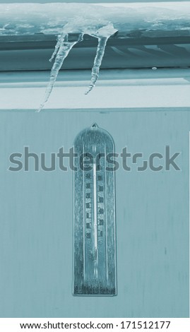 Frozen thermometer over a wall, under ice and snow
