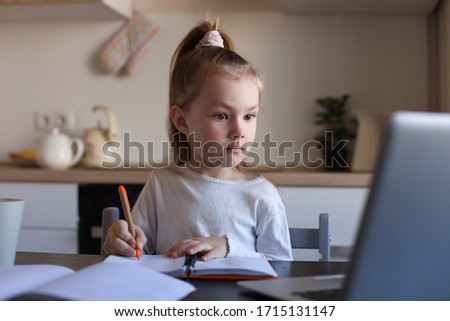 Serious little girl handwrite study online using laptop at home, cute happy small child take Internet web lesson or class on PC.
