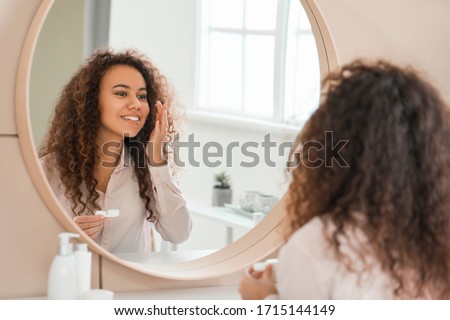 Young African-American woman putting in contact lenses at home Royalty-Free Stock Photo #1715144149