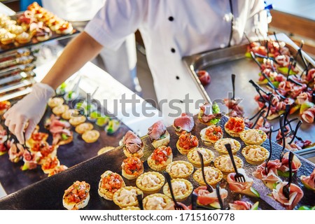 Hands of a cater in white gloves laying out sandwiches Royalty-Free Stock Photo #1715160778