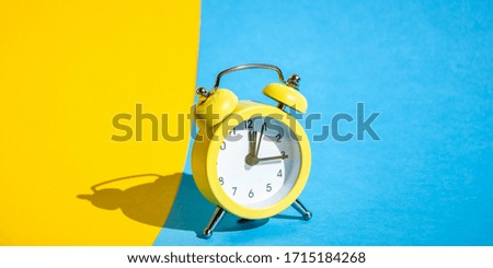 Yellow vintage alarm clock on a blue and yellow background with selective focus, copy space for text, The concept of time, delay, morning rise, the appointed meeting, Ringing twin bell vintage classic