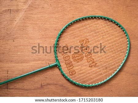 Badminton rackets are placed on the wood background which has a message on its. Sport at home. Stay at home.
