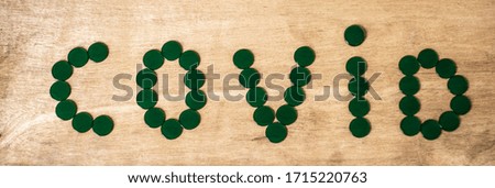 Green small  acrylic sheets are  arranged in COVID word on the wood table. COVID  epidemic concept.
