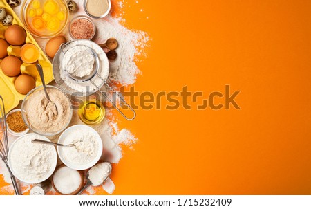 Baking ingredients for dough on yellow color background, top view of flour, eggs, butter, sugar and kitchen utensils for homemade baking. Cooking concept banner with copy space for text Royalty-Free Stock Photo #1715232409
